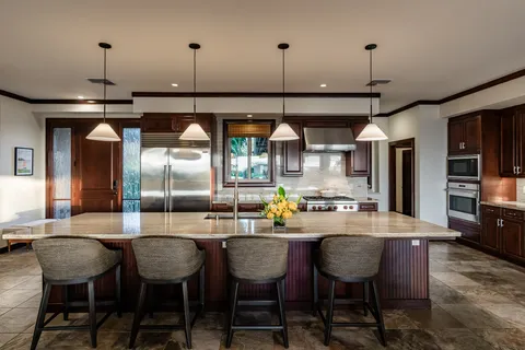 a kitchen with stainless steel appliances kitchen island granite countertop a dining table chairs and white cabinets