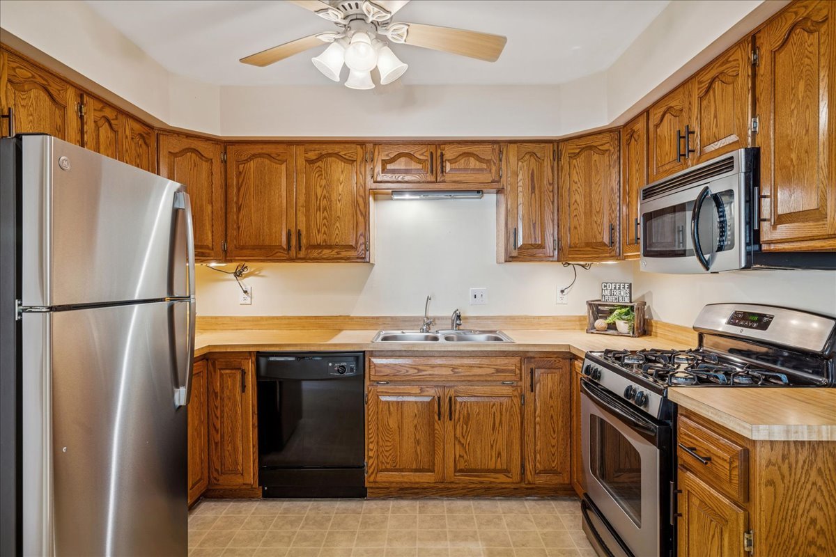 511 Coventry Lane, Unit 2 Crystal Lake, IL 60014 - Photo 3 of 40 a kitchen with stainless steel appliances granite countertop a stove top oven a refrigerator a sink and dishwasher with wooden floor