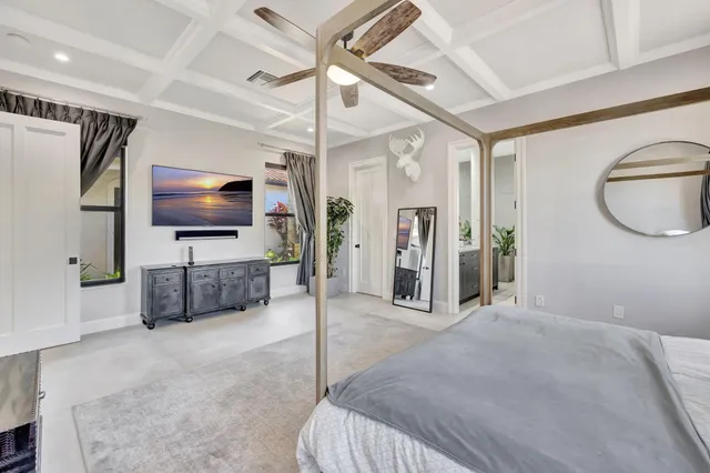 a large bed sitting in a bedroom next to a window and a chandelier