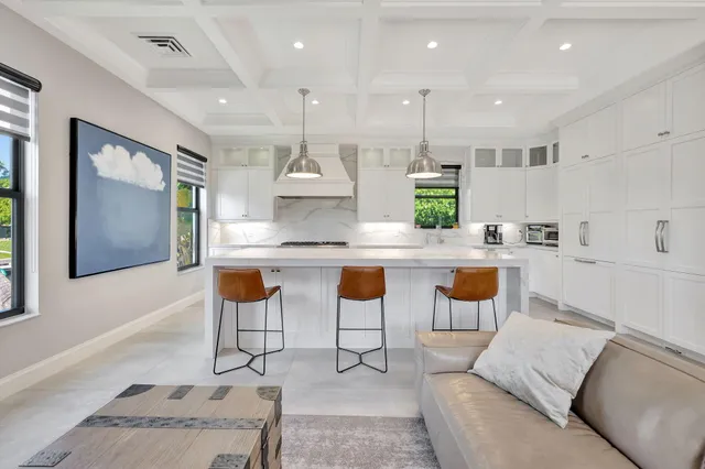 a large white kitchen with a large island oven a stove a sink a dining table and chairs