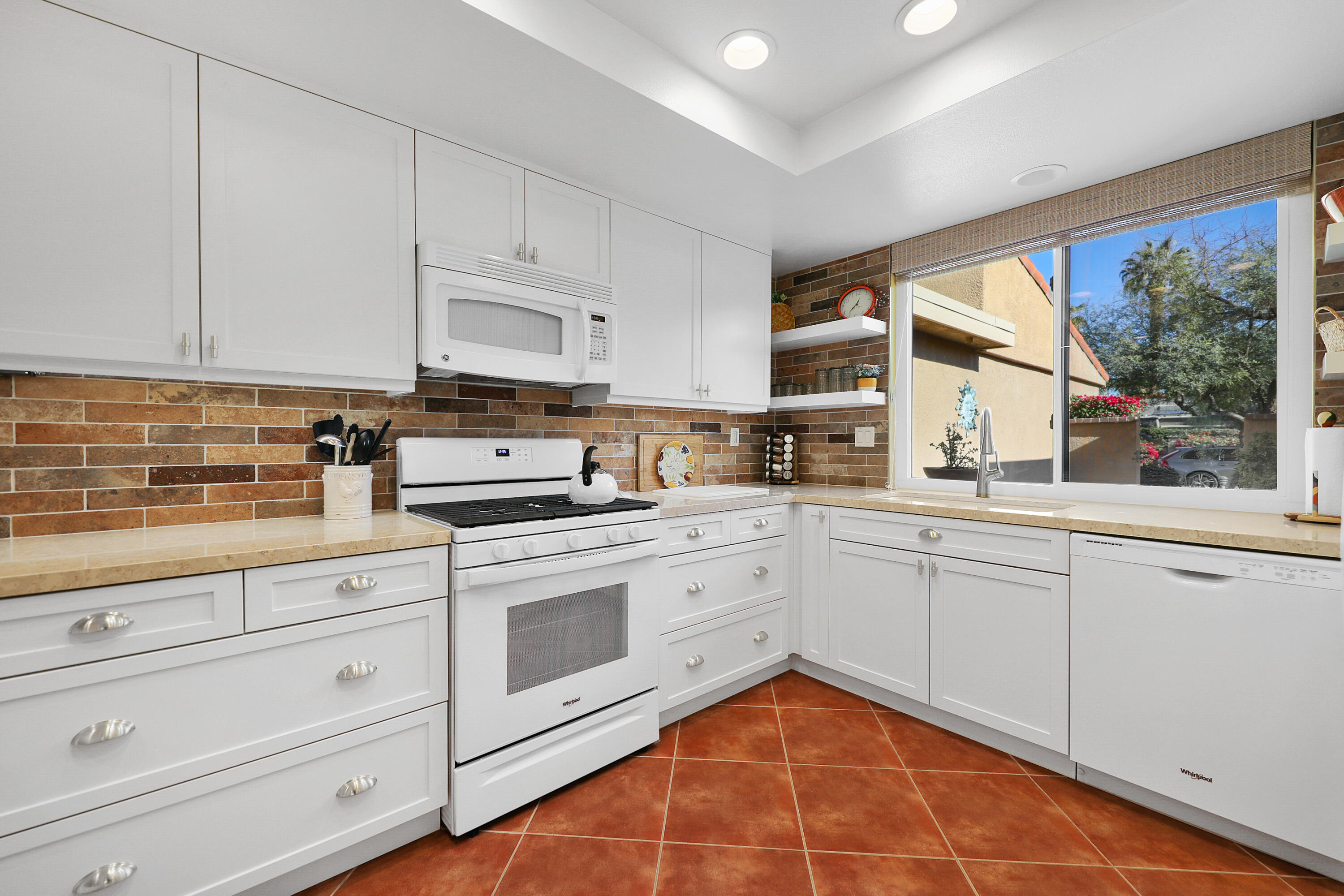 23 La Ronda Drive Rancho Mirage, CA 92270 - Photo 10 of 34 a kitchen with granite countertop white cabinets stainless steel appliances a sink and a window