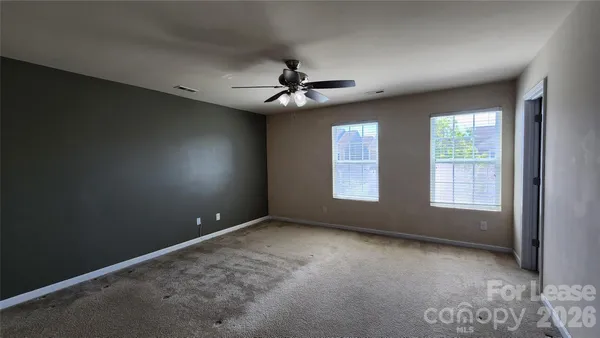 an empty room with windows and fan