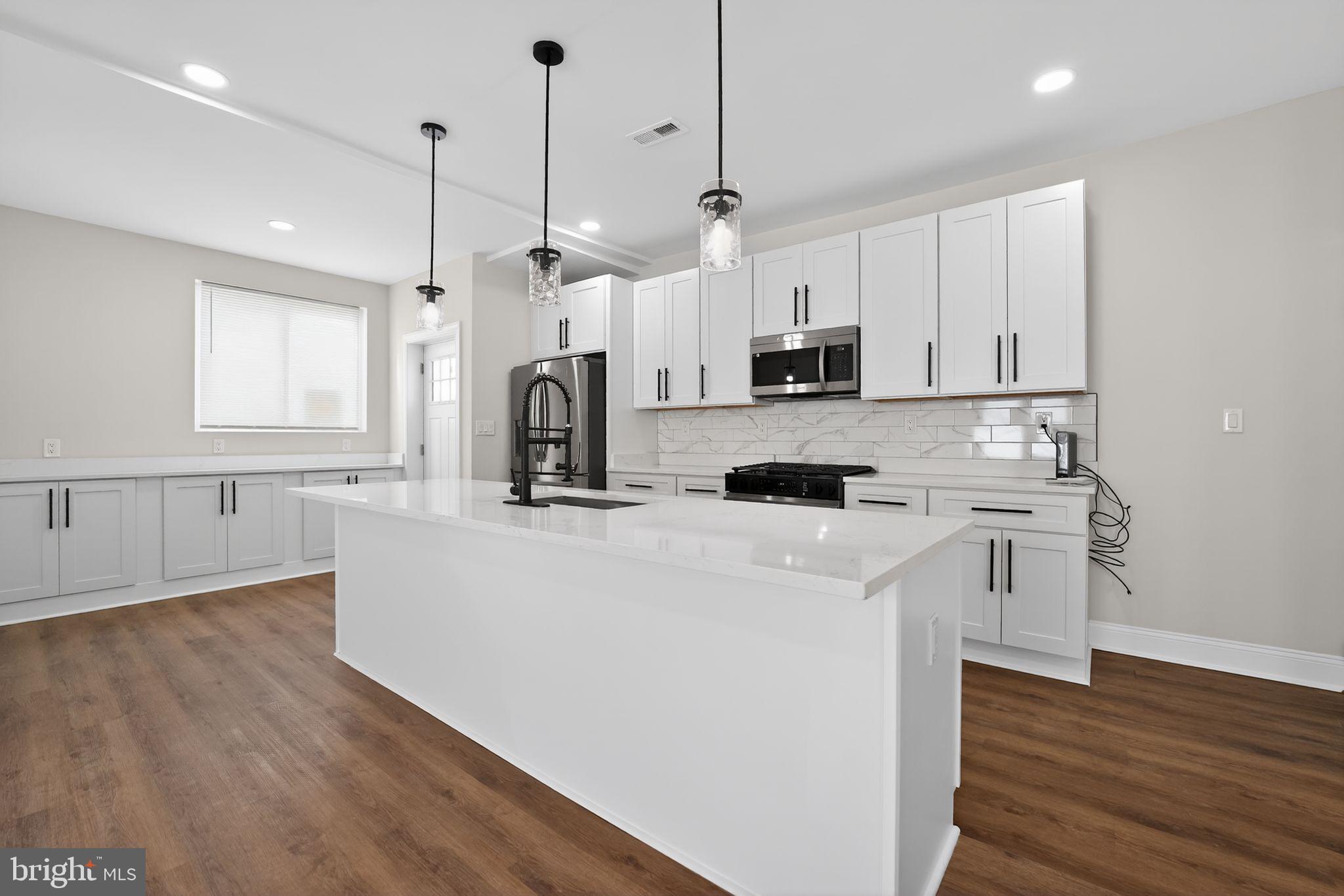 2911 Pinewood Avenue Baltimore, MD 21214 - Photo 7 of 30 a kitchen with stainless steel appliances white cabinets a sink a stove a refrigerator and island