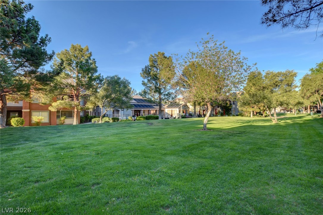 555 East Silverado Ranch Boulevard, Unit 2124 Las Vegas, NV 89183 - Photo 37 of 47 A verdant community lawn framed by mature trees and charming residences under a clear sky.