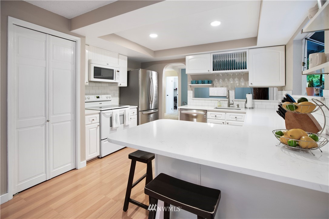 23625 48th Avenue Southeast Bothell, WA 98021 - Photo 16 of 40 a kitchen with stainless steel appliances a stove a sink a refrigerator white cabinets and wooden floor