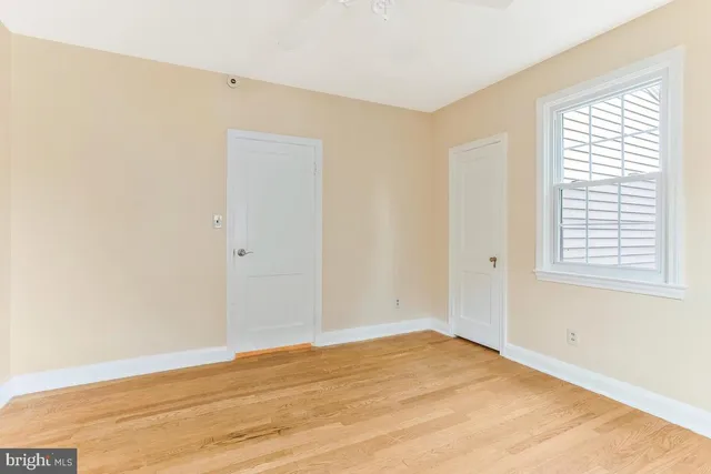 a view of empty room with wooden floor and fan
