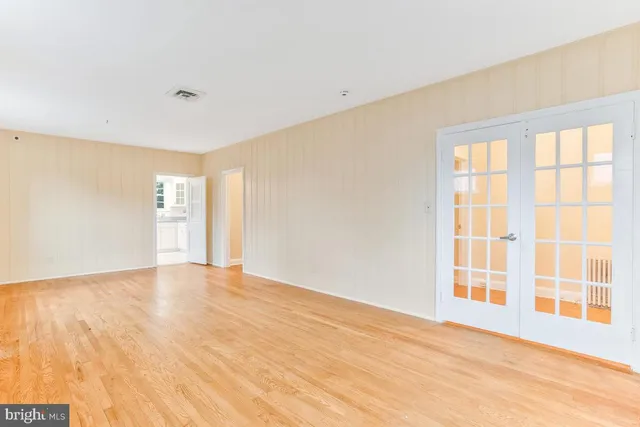 a view of an empty room with wooden floor with windows