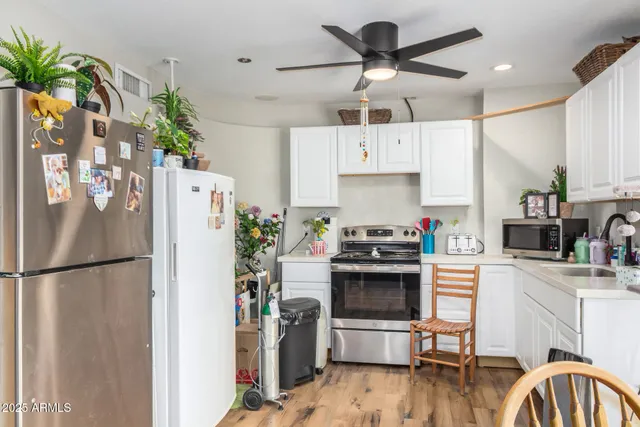 a kitchen with stainless steel appliances a stove a refrigerator and a dining table with wooden floor