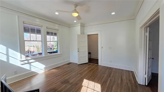 a view of empty room with wooden floor and fan