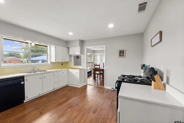 a kitchen with granite countertop a refrigerator a sink dishwasher a stove and white countertops with wooden floor