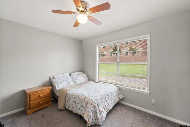 a view of a bedroom with a ceiling fan and a large window