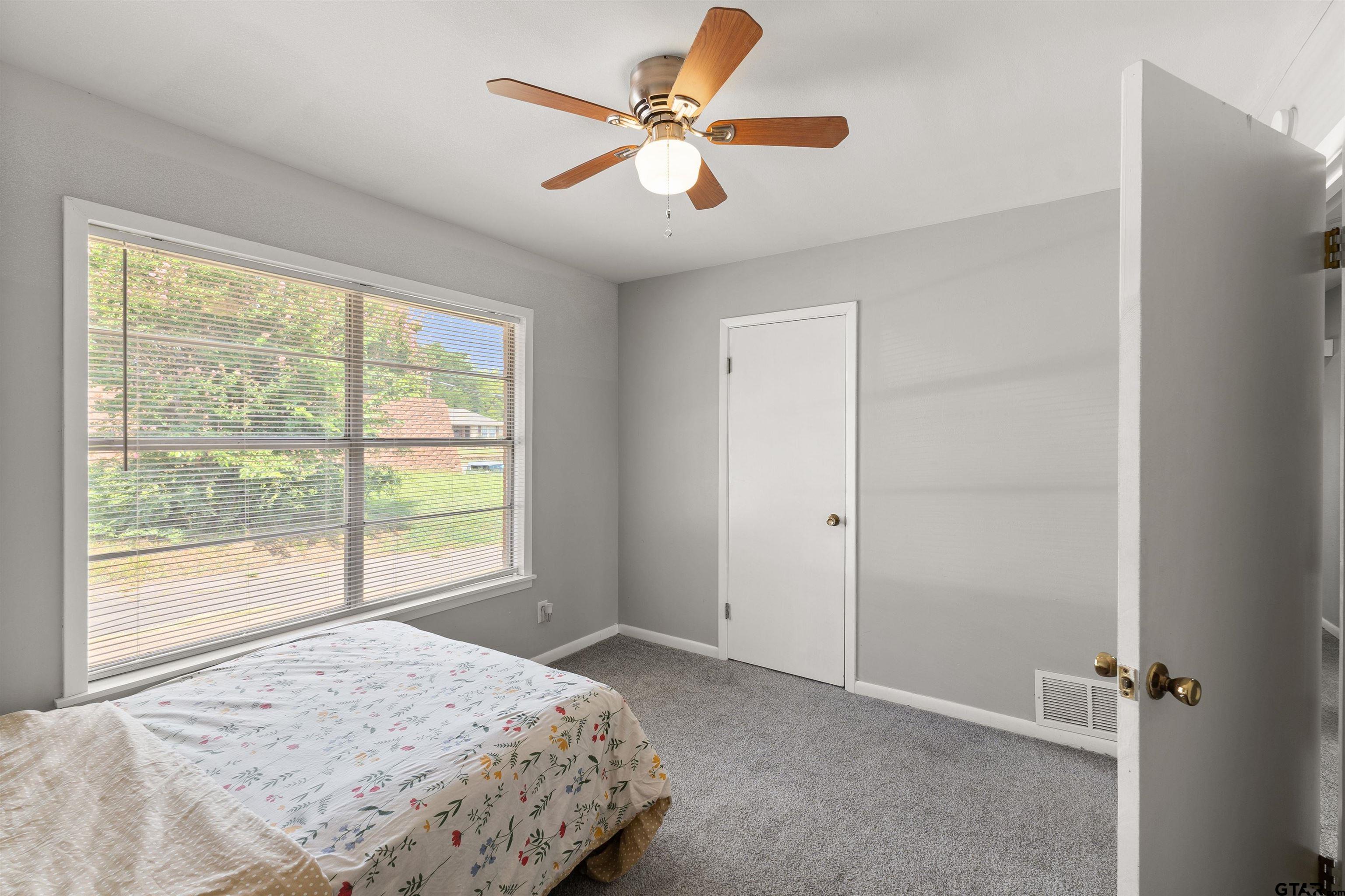 910 West Vance Street Tyler, TX 75702 - Photo 10 of 26 a view of a bedroom with a ceiling fan and a large window