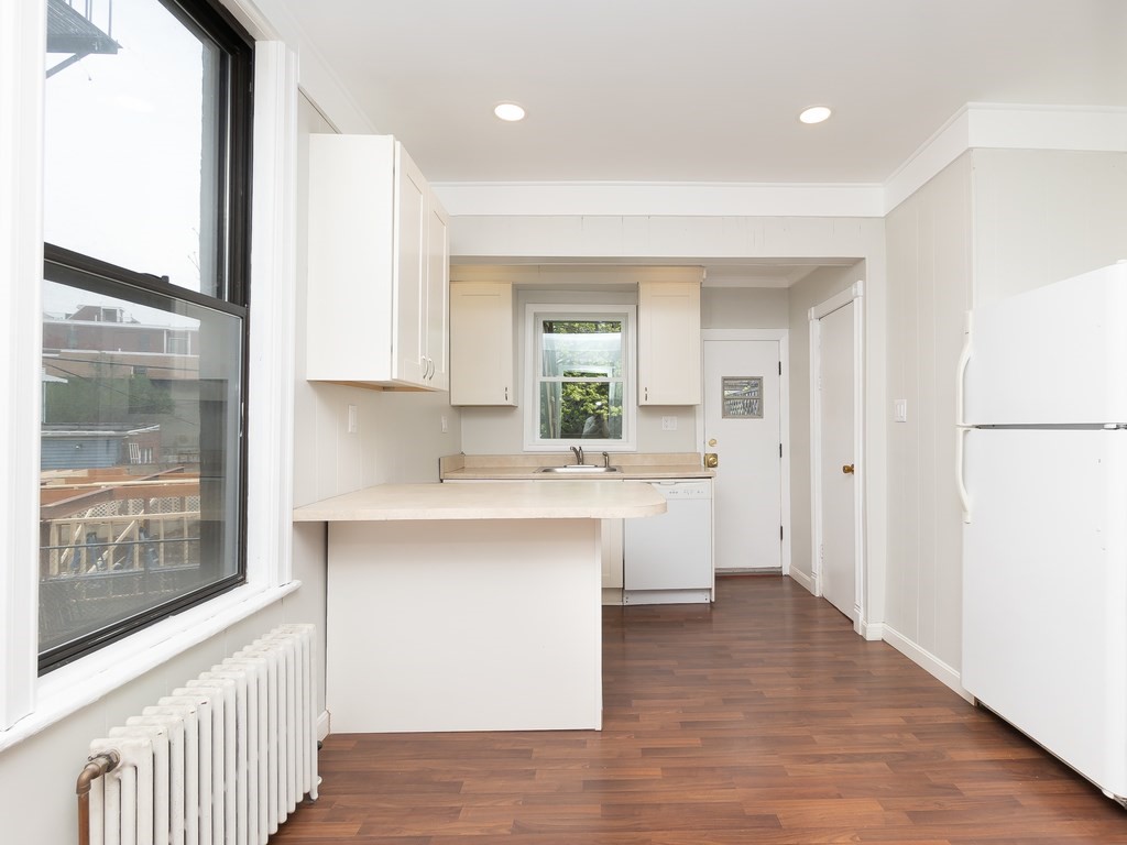 289 Meridian Street, Unit 2 Boston, MA 02128 - Photo 6 of 16 a kitchen with a sink cabinets stainless steel appliances and a window
