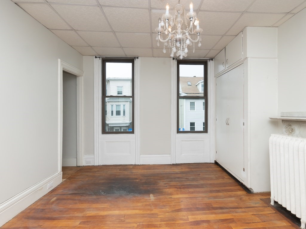 289 Meridian Street, Unit 2 Boston, MA 02128 - Photo 9 of 16 a view of an empty room with wooden floor and a chandelier