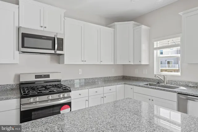 a kitchen with granite countertop white cabinets and appliances