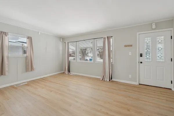 a view of an empty room with wooden floor and a window