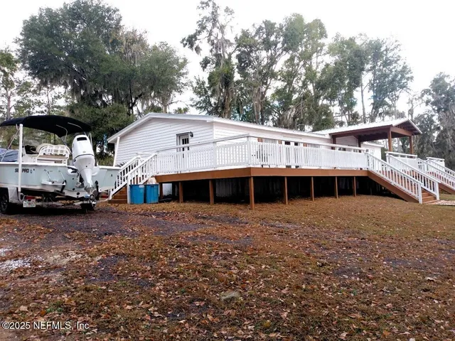 a view of house with a big yard and large trees