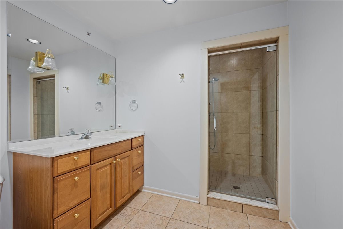 62 East Center Avenue, Unit 62 Lake Bluff, IL 60044 - Photo 13 of 19 a bathroom with a granite countertop sink a mirror and shower