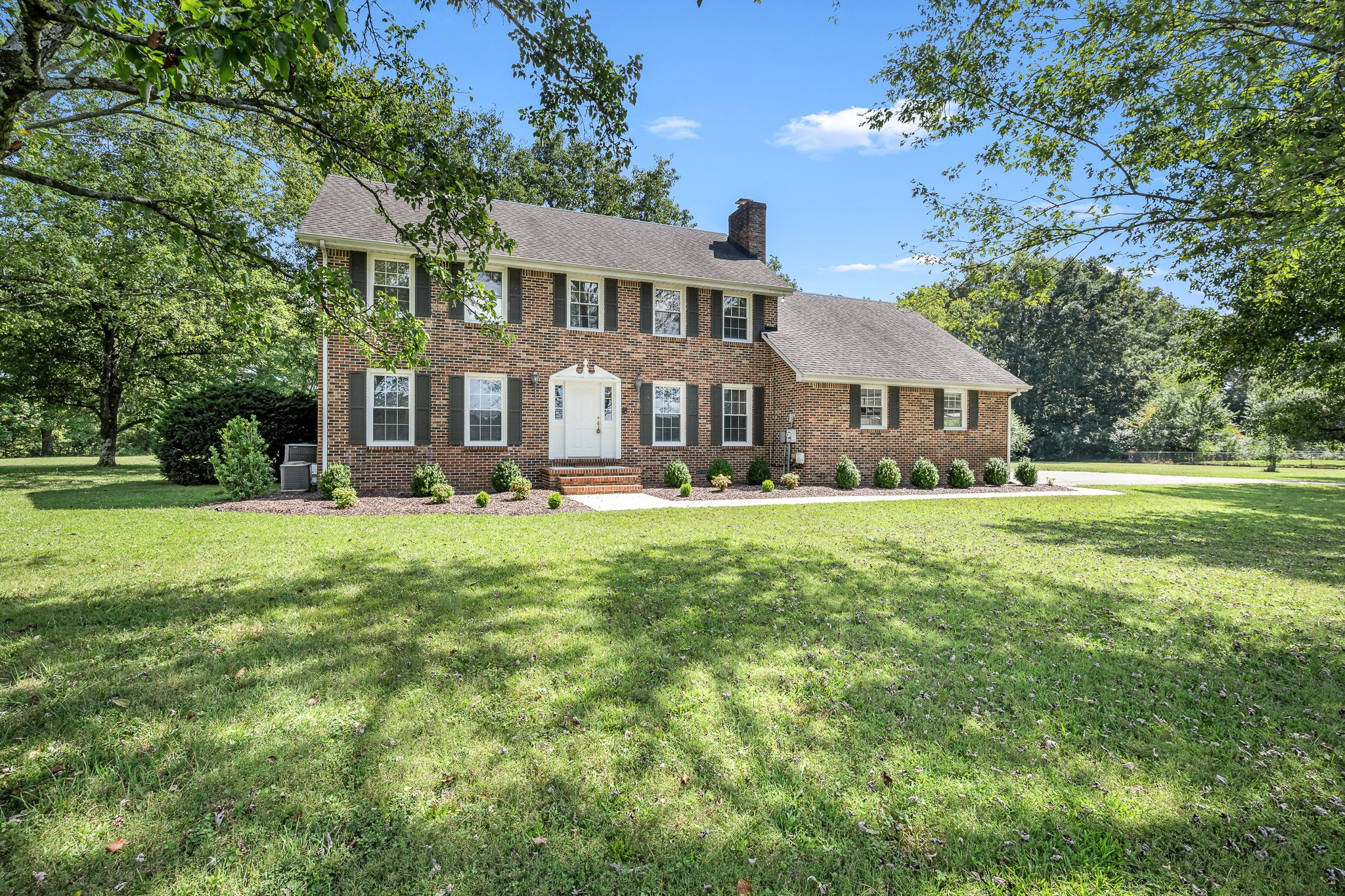 a front view of a building with garden and trees