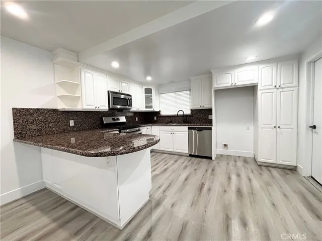 a kitchen with granite countertop a stove top oven a sink dishwasher and a refrigerator