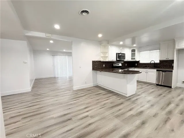 a kitchen with stainless steel appliances granite countertop a sink a stove top oven and white cabinets