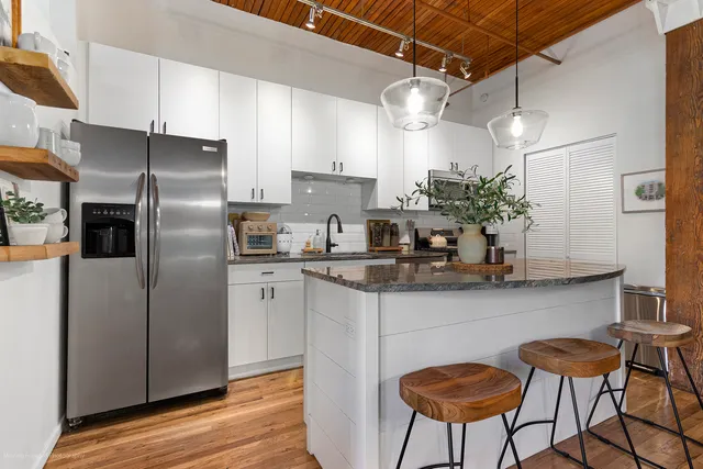 a kitchen with stainless steel appliances a refrigerator a stove a sink and chairs