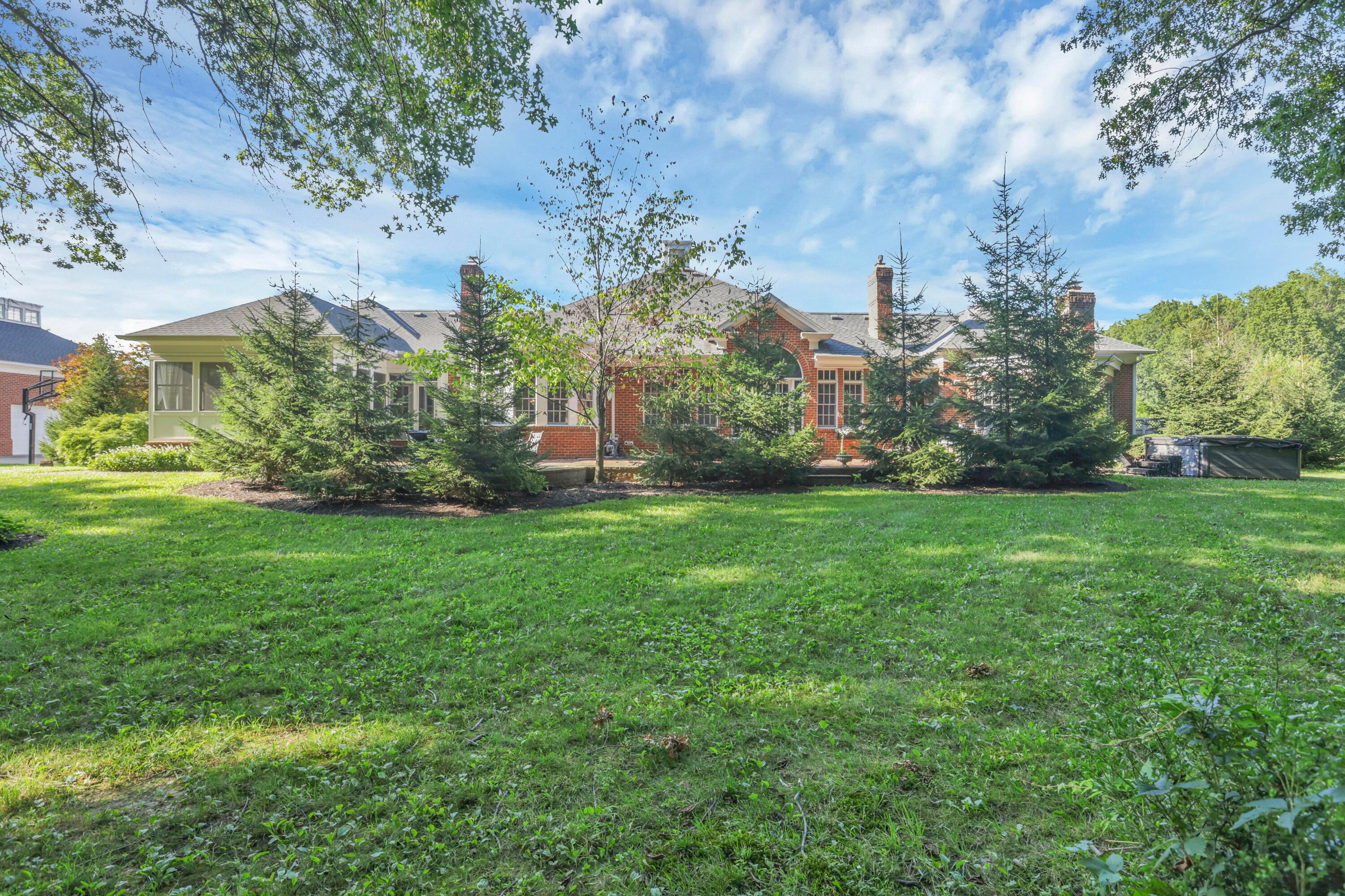 3575 State Rte 37 West Delaware, OH 43015 - Photo 102 of 106 Expansive green lawn with mature trees bordering a brick residence featuring multiple windows, a screened porch, and several chimneys