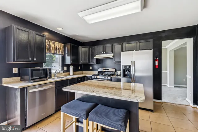 a kitchen with a refrigerator a sink dishwasher a stove with wooden cabinets and floor