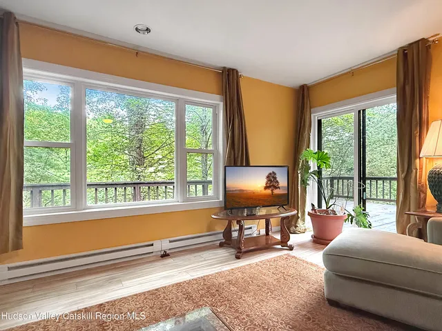 a living room with furniture a flat screen tv and a floor to ceiling window