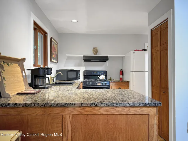 a kitchen with granite countertop kitchen island stainless steel appliances a sink and a refrigerator