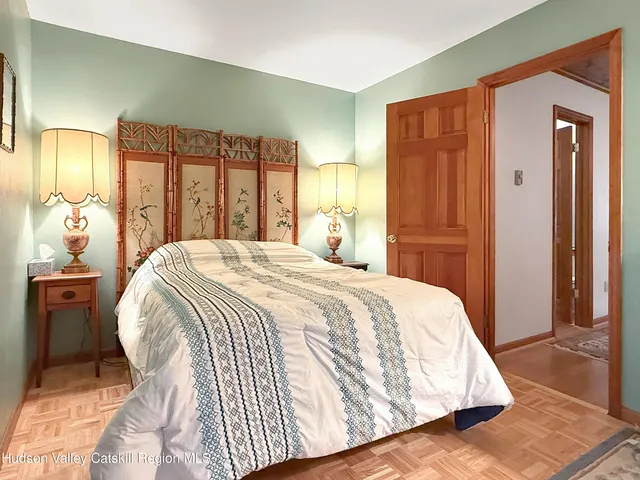 a spacious bedroom with a bed and dresser with mirror