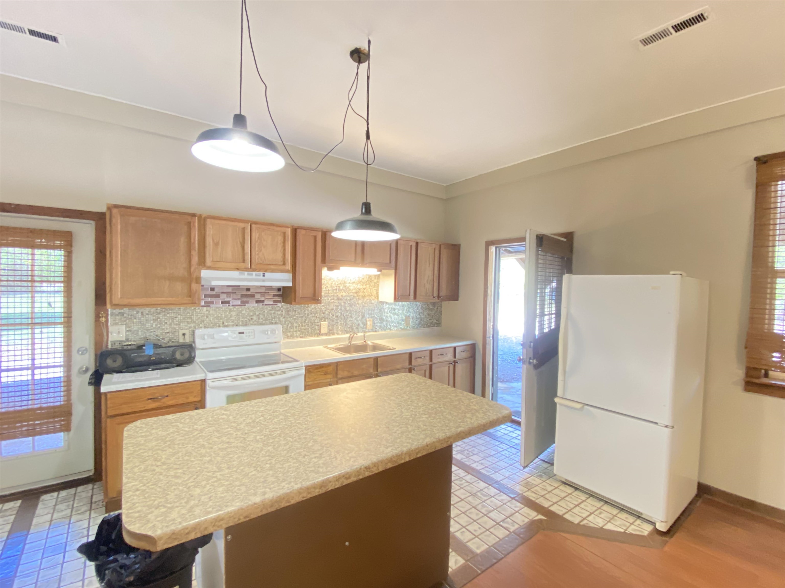 5610 Leapwood Enville Road Adamsville, TN 38310 - Photo 8 of 27 a kitchen with stainless steel appliances a stove a refrigerator a sink a dining table and chairs with wooden floor