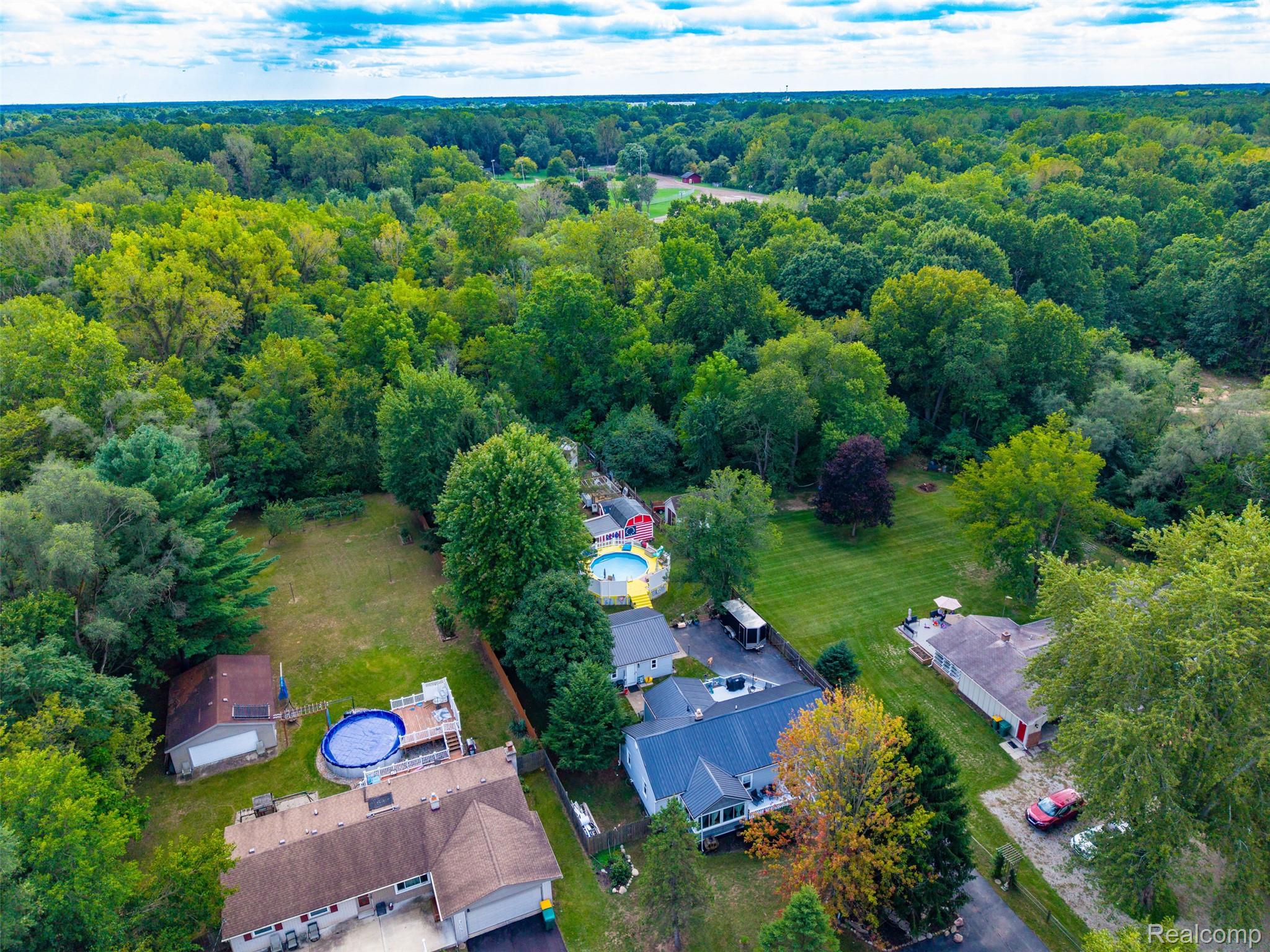 36739 Wick Road Romulus, MI 48174 - Photo 42 of 56 Expansive wooded surroundings with a residential property featuring a blue-lined above-ground pool with an attached deck