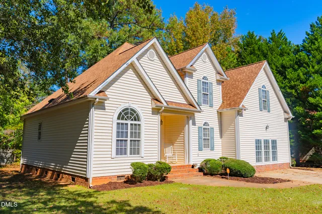 a view of a yard in front of a house with plants and trees