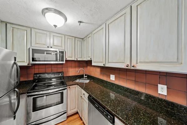 a kitchen with granite countertop white cabinets and stainless steel appliances