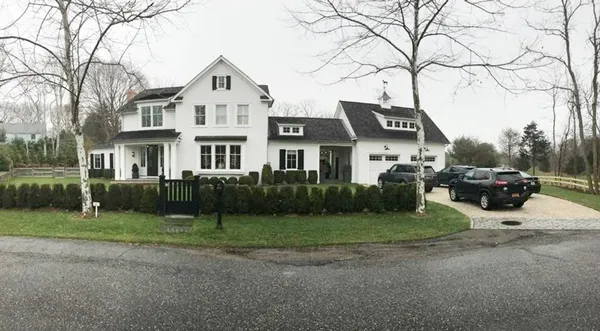 a front view of a house with a garden and trees