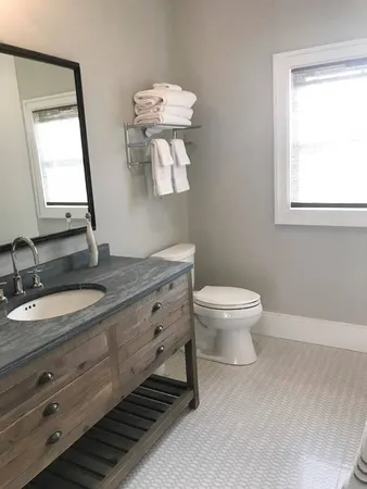 a bathroom with a granite countertop toilet a sink and a mirror