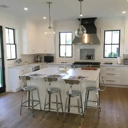 a kitchen with stainless steel appliances granite countertop a stove a sink a oven a dining table and chairs with wooden floor