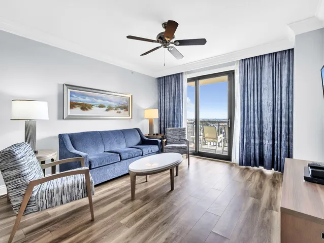 a living room with furniture a flat screen tv and kitchen view