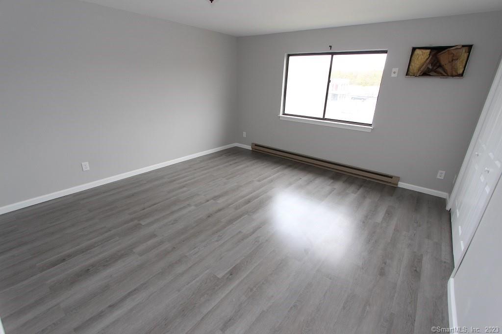 1400 Meriden Road, Unit 52 Waterbury, CT 06705 - Photo 12 of 21 an empty room with wooden floor and windows