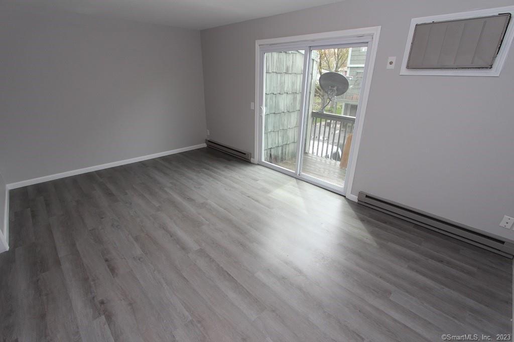 1400 Meriden Road, Unit 52 Waterbury, CT 06705 - Photo 4 of 21 an empty room with wooden floor and windows