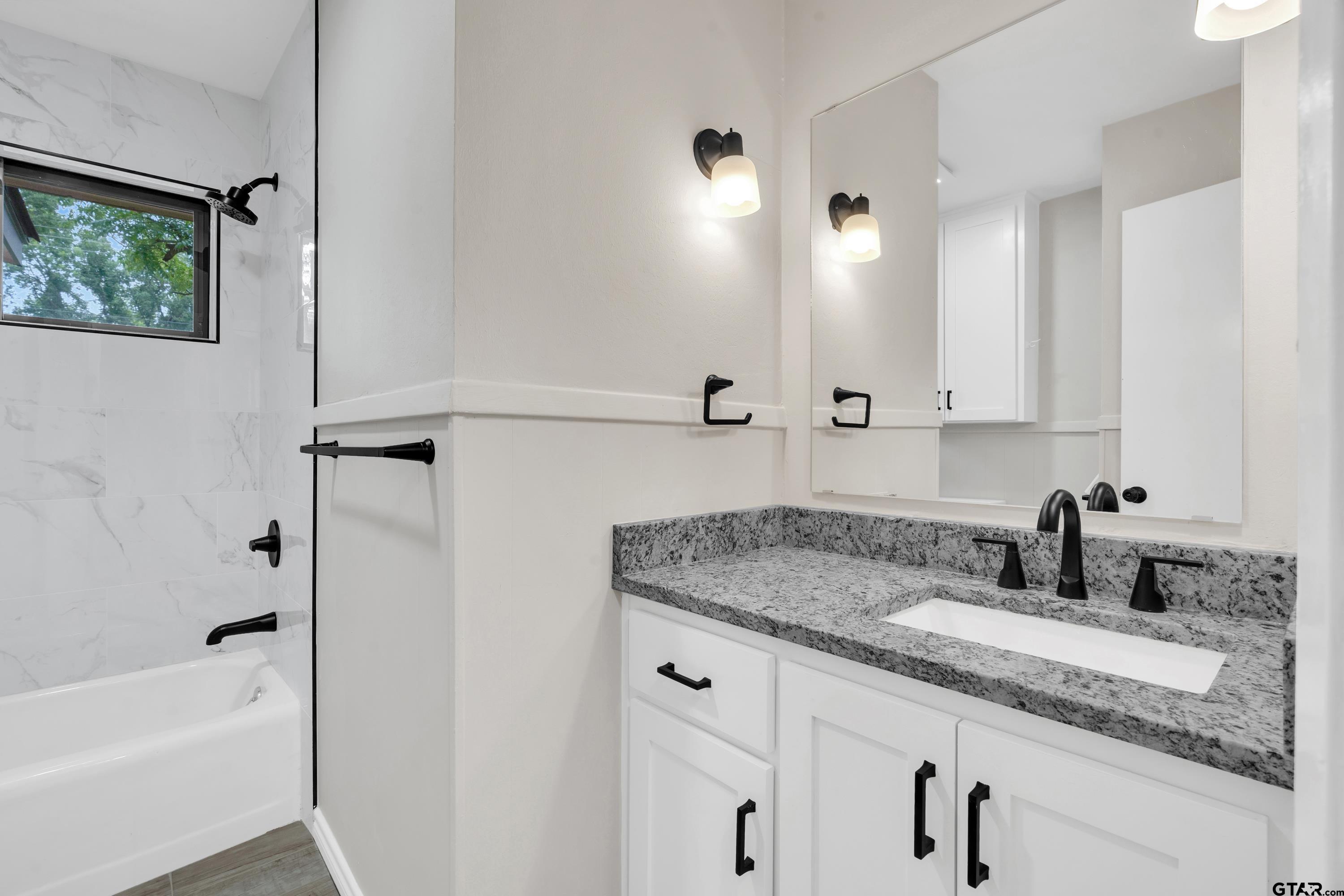 12813 Sunset Drive Tyler, TX 75704 - Photo 17 of 34 a bathroom with a granite countertop sink mirror and a bathtub