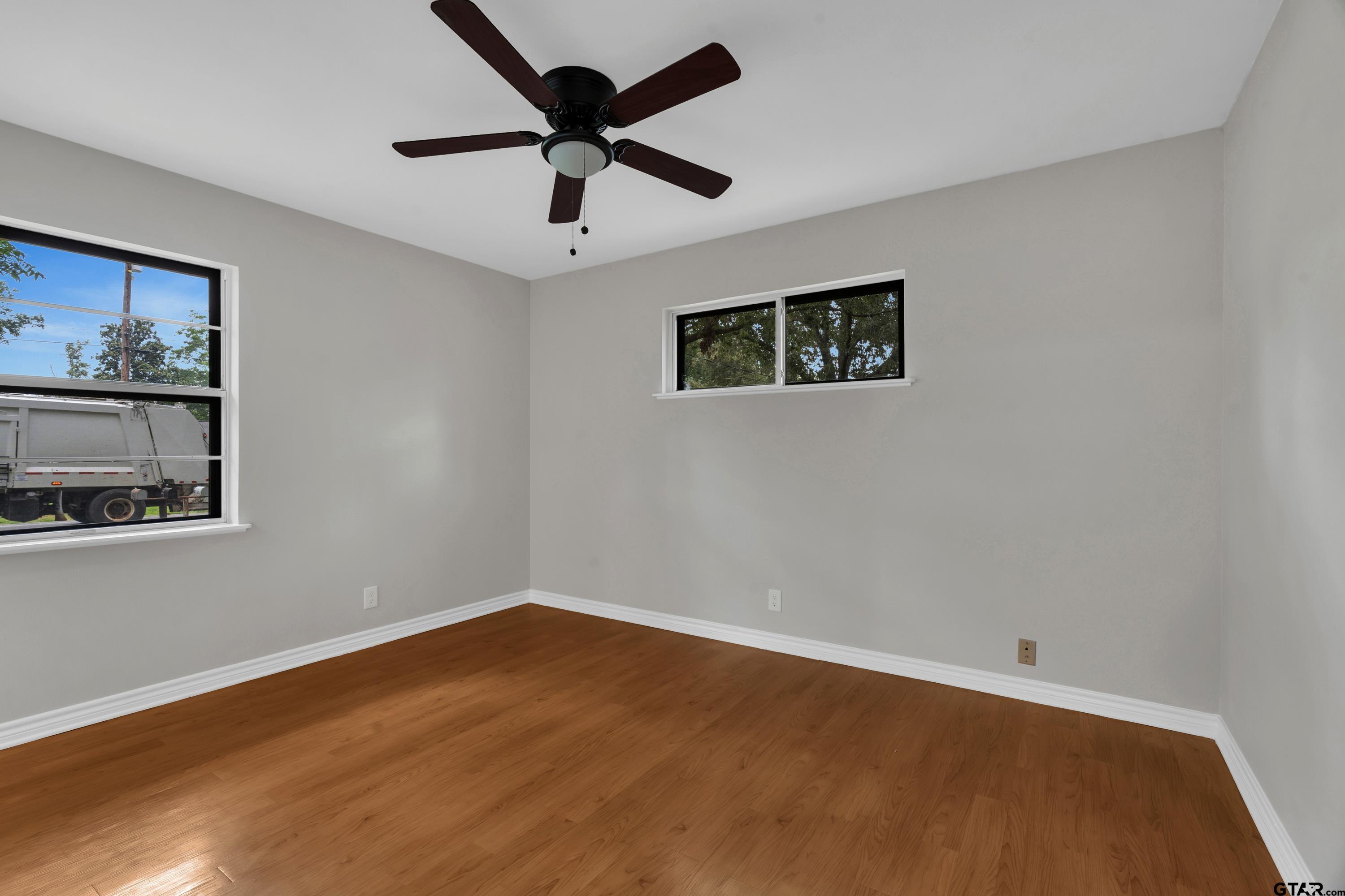 12813 Sunset Drive Tyler, TX 75704 - Photo 21 of 34 a view of an empty room with wooden floor and a ceiling fan