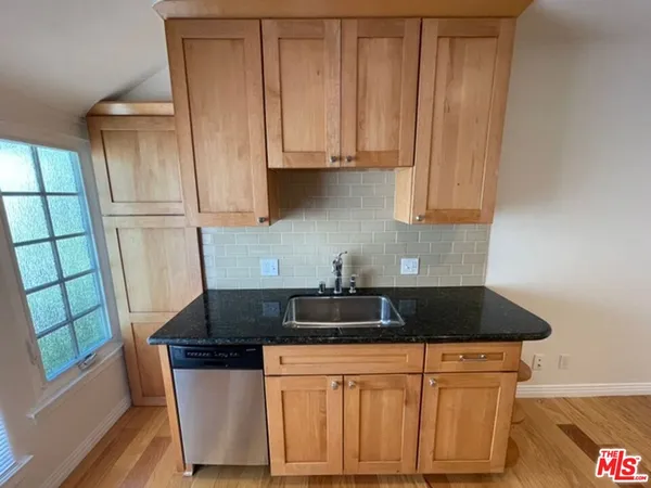 a kitchen with granite countertop a sink stove and cabinets