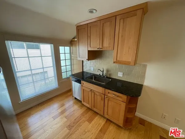 a kitchen with granite countertop wooden cabinets a sink and a wooden floor
