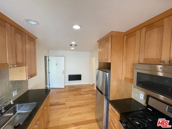 a kitchen with granite countertop a refrigerator stove and sink