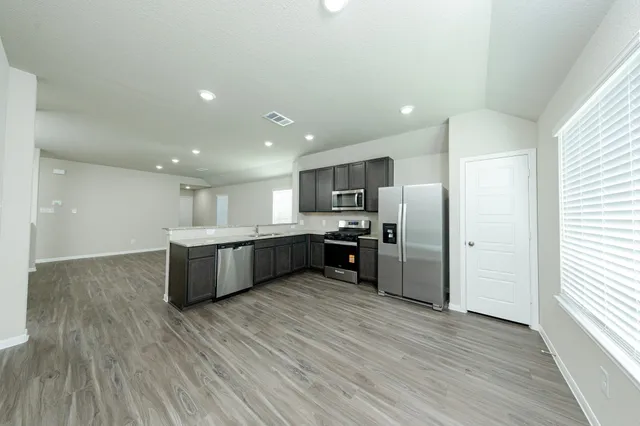 a large kitchen with a large counter top a sink stainless steel appliances and cabinets