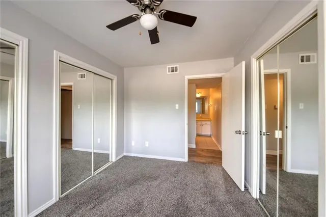 a view of a hallway with a chandelier fan and closet area