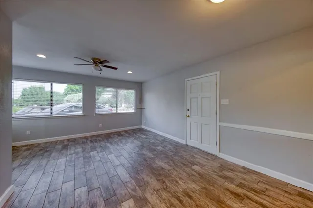 a view of an empty room with a window and wooden floor