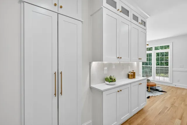 a kitchen with white cabinets and wooden floors